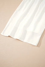 A flowy white silk scarf with soft folds complements flowy wide leg pants with drawstring waist for elegant style