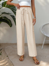 Cream-colored drawstring wide leg pants with subtle crinkled texture designed for machine wash cold care