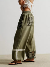 Olive green drawstring harem pants with intricate floral lace patchwork and delicate white lace trim on sides and cuffs