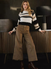 A cozy long-sleeved sweater with bold black white and beige stripes paired with high-waisted polyester wide leg cropped pants