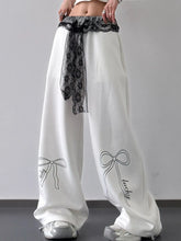 White wide leg pants with black lace belt trim and embroidered lucky bow designs on each leg