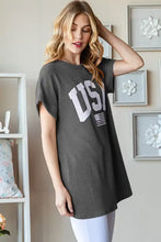 Woman modeling dark grey graphic short sleeve top with bold USA graphic
