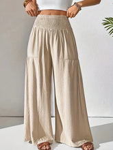 Beige smocked waist wide leg pants with smocked waistband, two front pockets, made from lightweight fabric