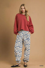 A pair of loose-fitting white and blue umgee scenic print casual sweatpants with a relaxed fit and scenic print design
