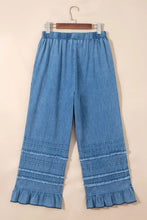 Light blue chambray pants featuring a wide leg fit with a ruffled hem and decorative stitching