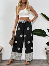 Black boho print wide leg pants with white geometric embroidery and lace trim at waistband and hem