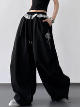 Black wide leg pants with drawstring lace waistband and embroidered rose detail on the side for stylish comfort