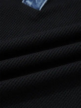Black waffle-knit fabric with denim trim button detail on a textured ribbed denim trim button top