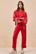 Red sweatshirt with white drawstrings and side stripes featuring lined bow details fleece design by bibi