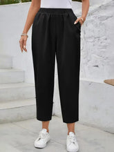 Black high rise elastic waist pants with loose fit, cropped length, and comfortable elastic waistband design