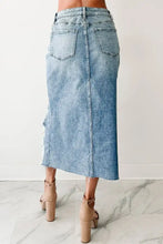 A light-wash distressed asymmetrical denim skirt with a straight cut frayed hem and two back pockets shown from the back