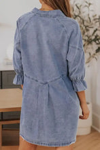 A light blue denim dress with a distressed collared neck and collared neck flounce sleeve detail and ruffled cuffs