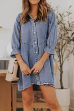 A light blue denim dress with distressed collared neck button front puffed sleeves and ruffled cuffs flounce style