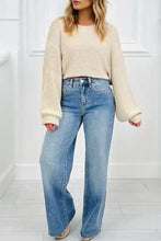 Beige textured knit cropped sweater with ribbed cuffs worn over blue denim tummy control raw hem jeans