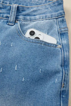 White smartphone peeking out of blue denim distressed detail tummy control raw hem jeans pocket
