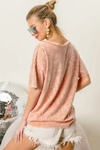 Woman in distressed peach t-shirt with American flag graphic and denim shorts