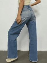 Blue denim bootcut jeans with distressed raw hems and subtle distressing offering versatile pairing advice