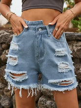 Distressed raw hem denim shorts with light wash and asymmetrical waistline