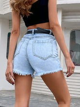 Distressed raw hem denim shorts with frayed hems and black belt