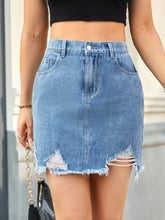 A light blue denim skirt with distressed raw hem, mid-thigh length and side pockets in a raw hem style