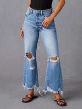 Light-wash denim flare jeans with distressed raw hem, intentional knee rips, and frayed hems for a casual look