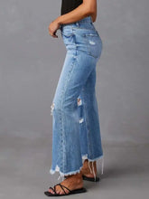 Light-wash denim flare jeans with distressed raw hem and high-rise wide-leg design featuring frayed hems