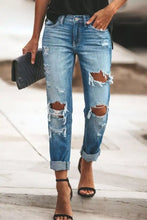 Blue distressed straight leg jeans made of denim with rolled cuffs and multiple ripped details