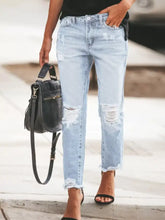 Light-wash denim ankle jeans featuring a unique distressed wash with ripped knees and frayed hems