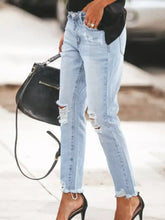 Light-wash denim ankle jeans with unique distressed wash featuring ripped knees and frayed hems
