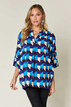 A woman wearing a vibrant blue white and dark purple double take full size geometric notched half sleeve blouse