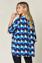 A woman wears a vibrant blue and white geometric patterned double take full size notched half sleeve blouse