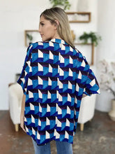 Blue and white geometric patterned short-sleeve blouse with a modern bold design and notched half sleeves