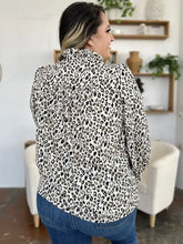 A woman wearing a black and white leopard print long sleeve blouse with ruffled sleeves called double take full size leopard blouse