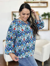 A vibrant long-sleeved blouse with bold geometric ikat pattern in blue green red and white perfect for casual wear