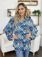 A vibrant long-sleeved double take blouse with bold blue teal red and white geometric ikat pattern