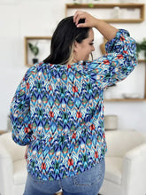 A vibrant long-sleeved blouse with balloon sleeves featuring a bold blue green ikat pattern with red accents