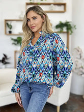 A vibrant long-sleeved double take blouse with bold geometric ikat pattern in blue, teal, red, and green