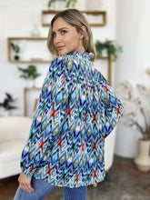 A vibrant long-sleeved double take full size printed balloon sleeve blouse with bold blue teal red and white geometric pattern