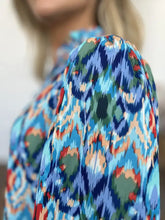 A vibrant blue green and red ikat printed double take full size blouse with balloon sleeves and flowing sheer fabric
