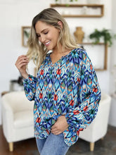 A vibrant blue red and green ikat patterned double take full size printed balloon sleeve blouse with long sleeves