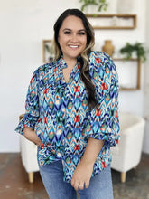 A vibrant long-sleeved blouse with bold geometric ikat pattern in teal blue red and green balloon sleeves