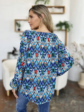 A woman wears a double take full size printed balloon sleeve blouse in vibrant blue green and red ikat pattern