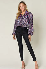 A woman wears a purple and pink floral double take full size printed balloon sleeve shirt paired with jeans size options