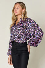 A woman wearing a double take full size printed balloon sleeve shirt with purple and pink floral print paired with jeans size