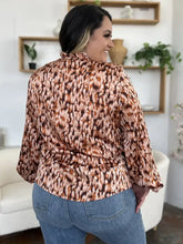 A woman wearing a double take full size printed ruffle trim balloon sleeve shirt in brown and beige leopard print