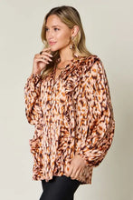 A women’s long-sleeved blouse with brown and beige leopard print ruffled neckline and cuffs, button closures