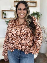 A plus-size woman wearing a double take full size printed ruffle trim balloon sleeve shirt in brown and peach abstract pattern
