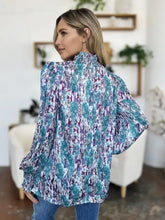 A woman wears a double take full size printed smocked long sleeve blouse with voluminous sleeves in teal purple