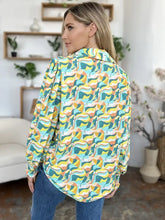 A woman wears a double take full size printed smocked long sleeve blouse with an abstract wave pattern in teal yellow orange and white