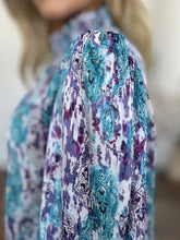 A woman wearing a double take full size printed smocked long sleeve blouse with turquoise purple and white paisley pattern